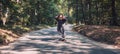 Skateboarder ride a longboard through the forest Ã¢â¬â panorama